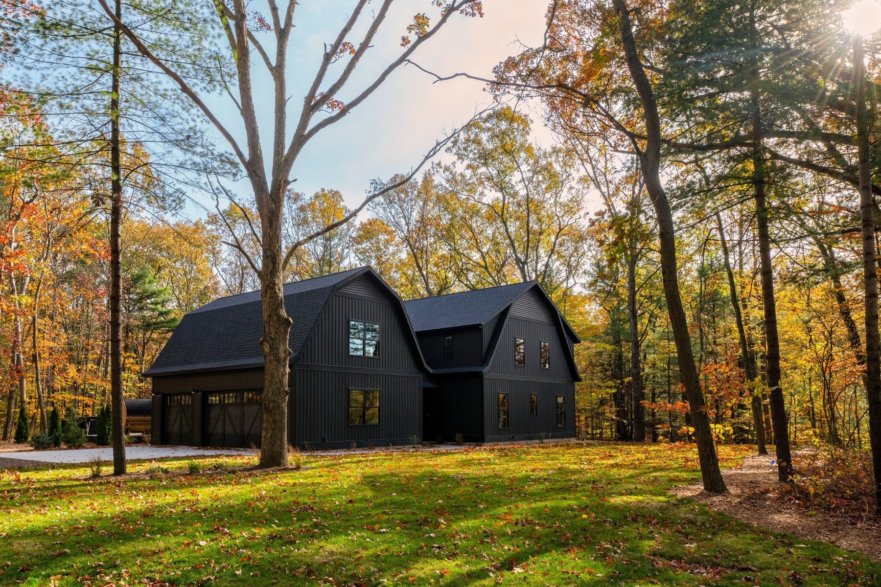 The black barn homes of Black Barn Ridge among autumn trees.