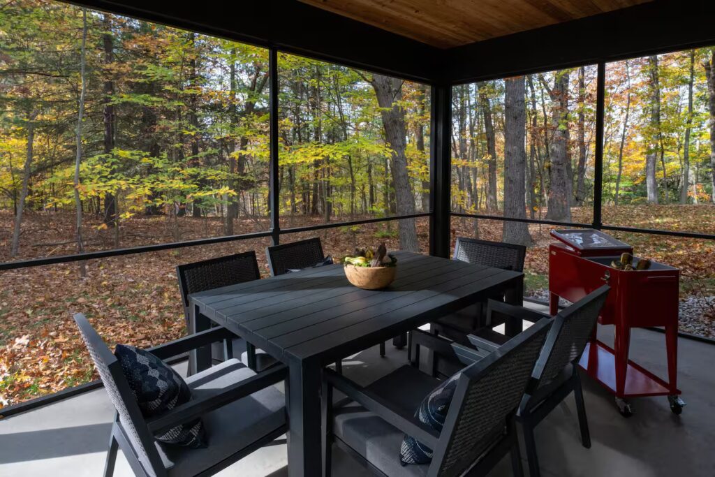 Screened porch with a dining table looking into the woods.