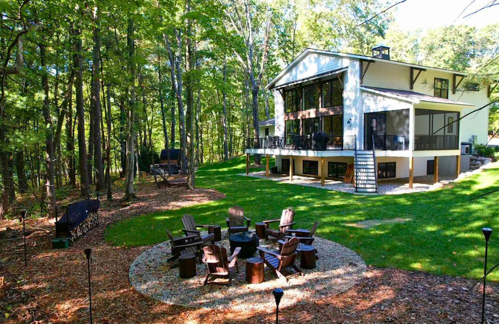The Dutch seen from the backyard fire pit among tall trees.