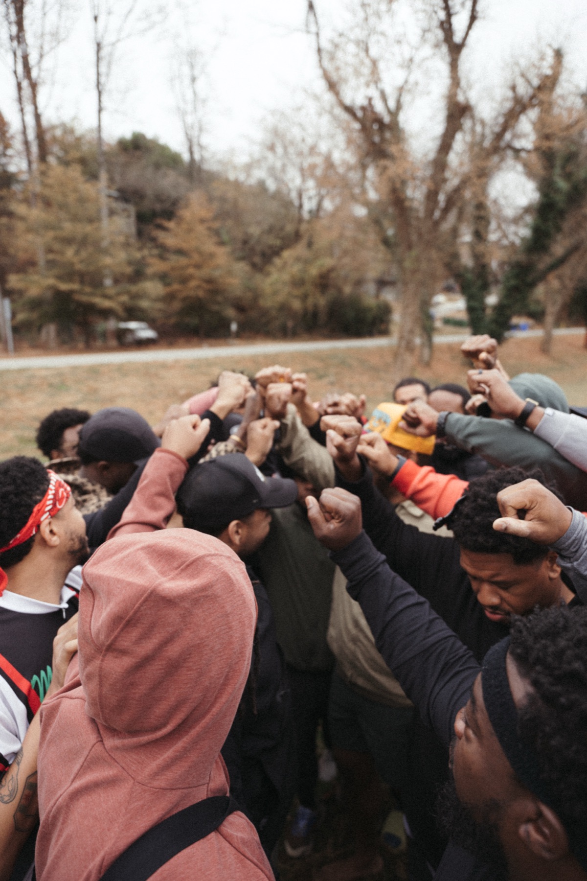 Men of The Healing in a huddle, fists raised together at the center.